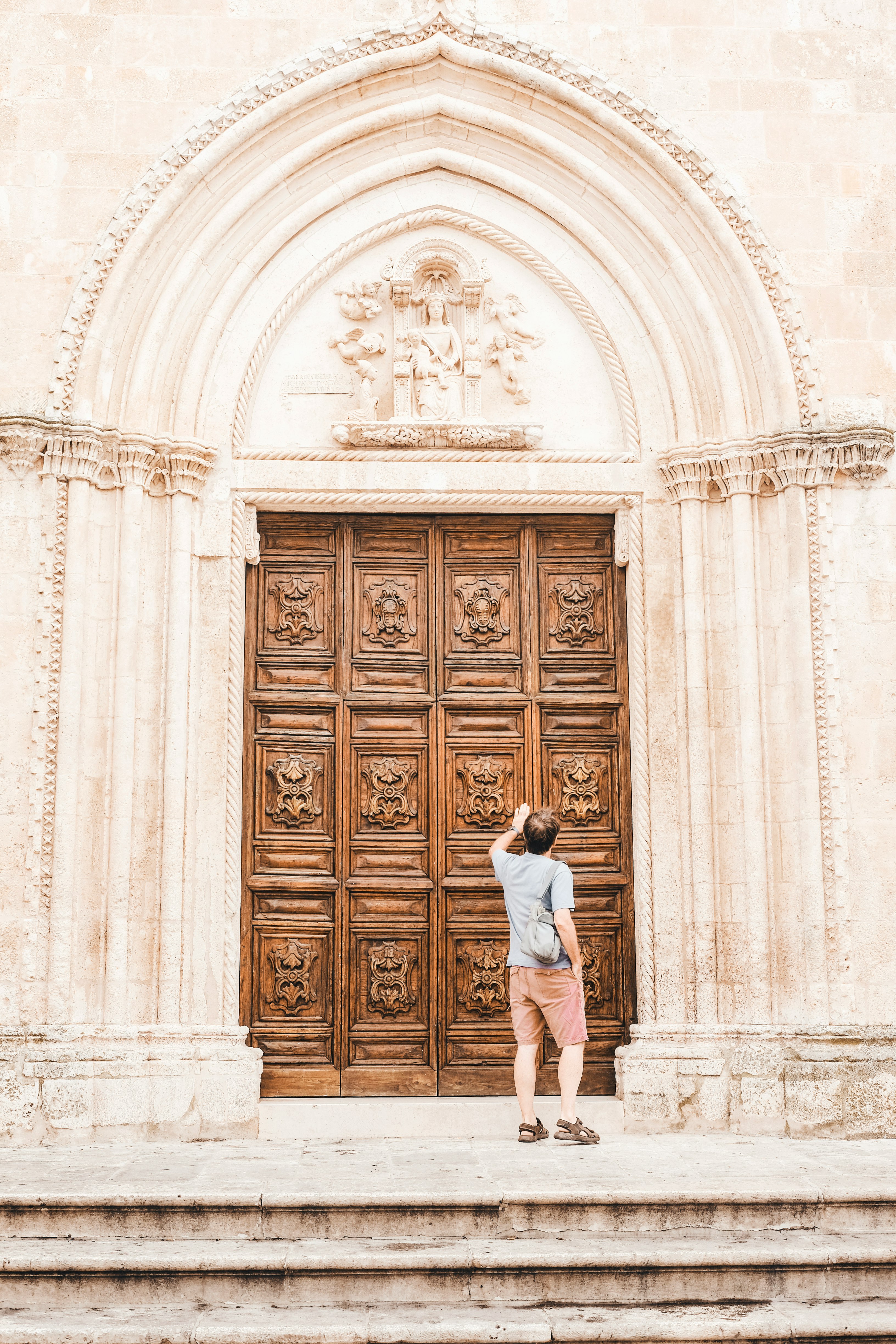 woman in white shirt standing in front of brown wooden door